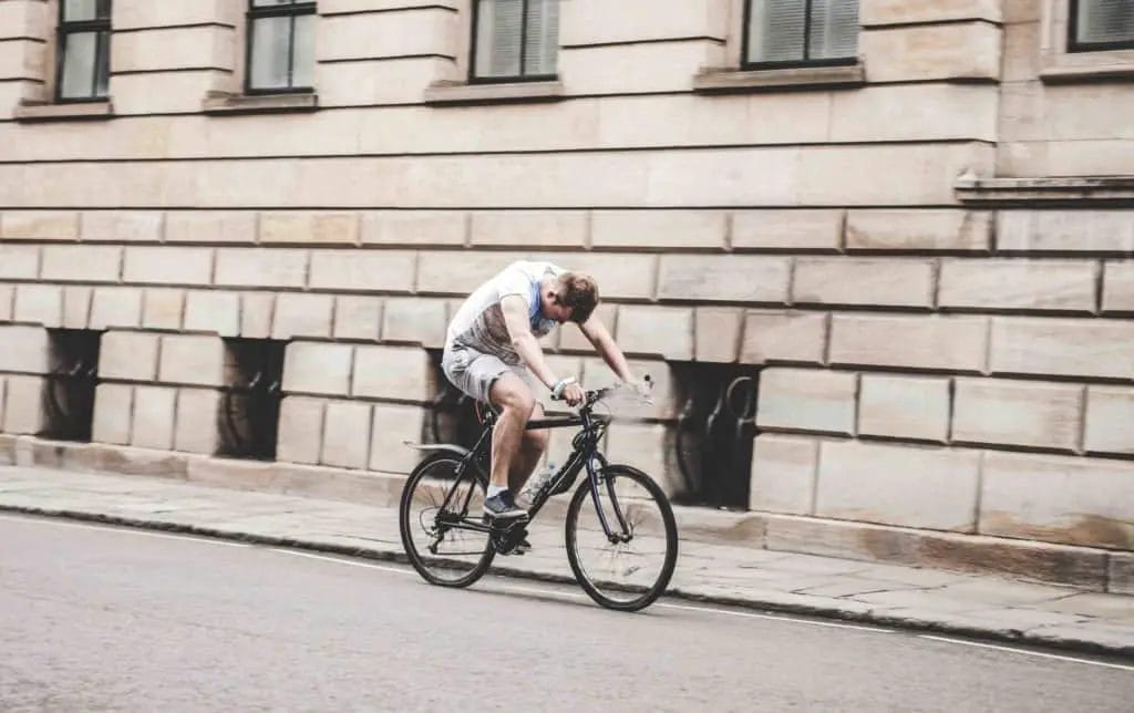 Cycling Knee Pain Explained - A cyclist with improper equipment and showing signs of improper form.